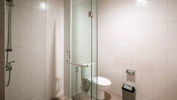 Un baño moderno con ducha envuelta en vidrio, inodoro y contenedor de basura.