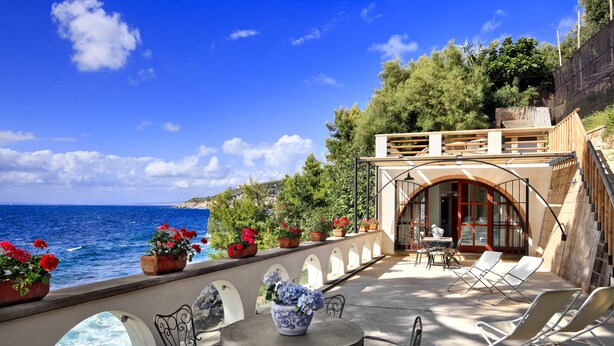 A terrace with a view of the sea, outdoor seating, and potted plants. - Appartamento Lobra (Massa Lubrense)
