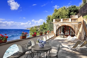 A terrace with a view of the sea, outdoor seating, and potted plants. - Appartamento Lobra (Massa Lubrense)