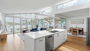 A modern kitchen with a large island, a dining area with a table and chairs, and a view of the outdoors.
