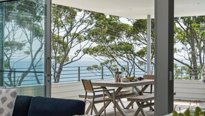 A balcony with a table, chairs, and a view of the sea.