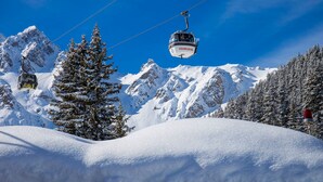 A cable car moving over a snowy mountain landscape with snow-covered trees and peaks in the background. - Courchevel 1850: 2-room flat, south-facing balcony, parking (Courchevel 1850)