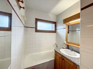 A bathroom with white tiled walls, a wooden vanity with a sink, and a large mirror above the vanity. - 2-room apartment + mountain corner near ski slopes with parking (Combloux)