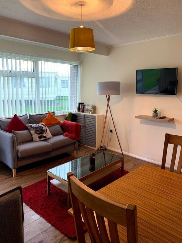 Relax in this stylish living room with a sofa, coffee table, and dining table, perfect for unwinding and enjoying the view.
