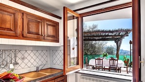 A kitchen with wooden cabinets, a sink, and a window overlooking an outdoor dining area.