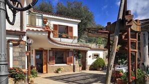A traditional Mediterranean-style building with a balcony, potted plants, and a rustic wooden structure.
