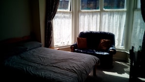 Ein Schlafzimmer mit Bett, Stuhl und einem fensterbepflanzten Fenster.