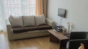 A modern living room with a sofa, a coffee table, a TV, and a chair. - Stunning 1-bed Apartment in Sunny Beach (Nessebar)
