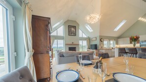 A dining area with a table set for four, a sofa, and a kitchen in the background. - Hillcrest - 8 Person Luxury House and Hot Tub (Hawick)