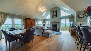 A spacious living area with a dining table, sofas, and a fireplace. - Hillcrest - 8 Person Luxury House and Hot Tub (Hawick)