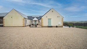 A two-story building with a gravel driveway and a clear sky. - Hillcrest - 8 Person Luxury House and Hot Tub (Hawick)