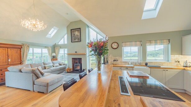 A spacious kitchen with a wooden island, a built-in oven, and a large window overlooking a scenic landscape. - Hillcrest - 8 Person Luxury House and Hot Tub (Hawick)