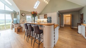 A spacious kitchen with a large island, bar stools, and a view of the outdoors. - Hillcrest - 8 Person Luxury House and Hot Tub (Hawick)