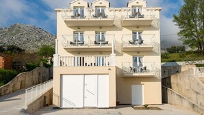 A multi-story building with balconies, a garage, and a stone wall. - Villa Samba (Zupa dubrovacka)