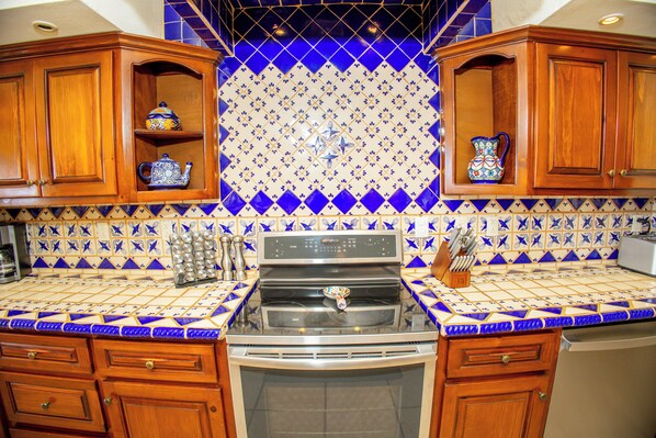 A kitchen with wooden cabinets, a stove, and a tiled backsplash.