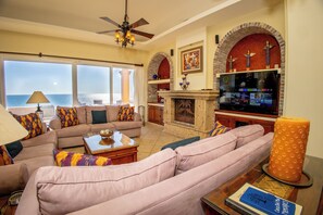 Relax in a spacious living room with a large sectional sofa, coffee table, and fireplace, offering a serene ocean view.
