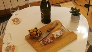 A round white table with a bottle of champagne, a wooden board with sliced meats, and a small potted plant. - 4* family apartment, terrace, garden and fireplace (Briançon)