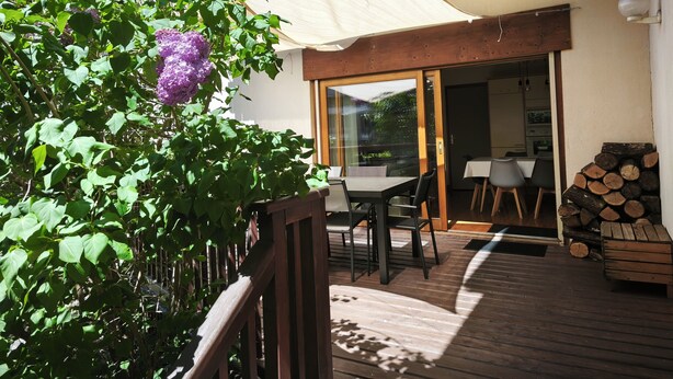 A wooden deck with a table and chairs, a covered area with a white canopy, and a pile of logs. - 4* family apartment, terrace, garden and fireplace (Briançon)