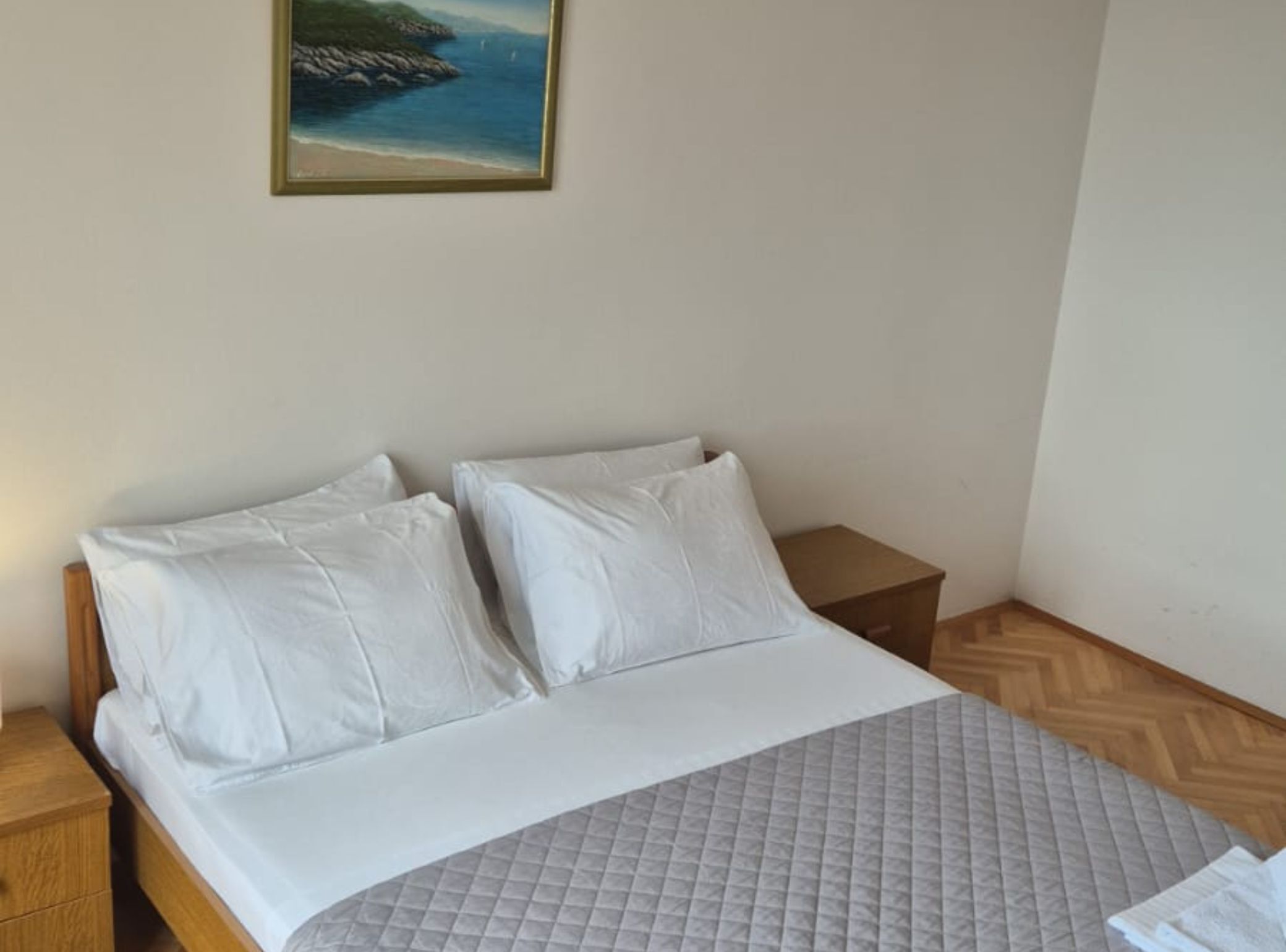 A neatly made bed with white linens in a hotel room.
