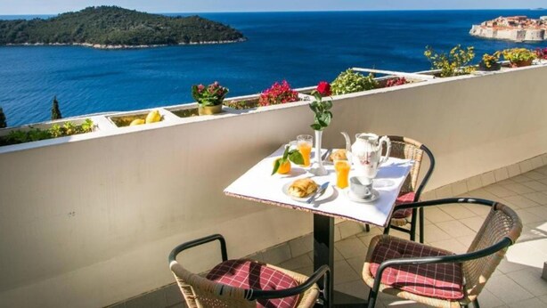 Una terraza con mesa lista para el desayuno, con vista al mar.
