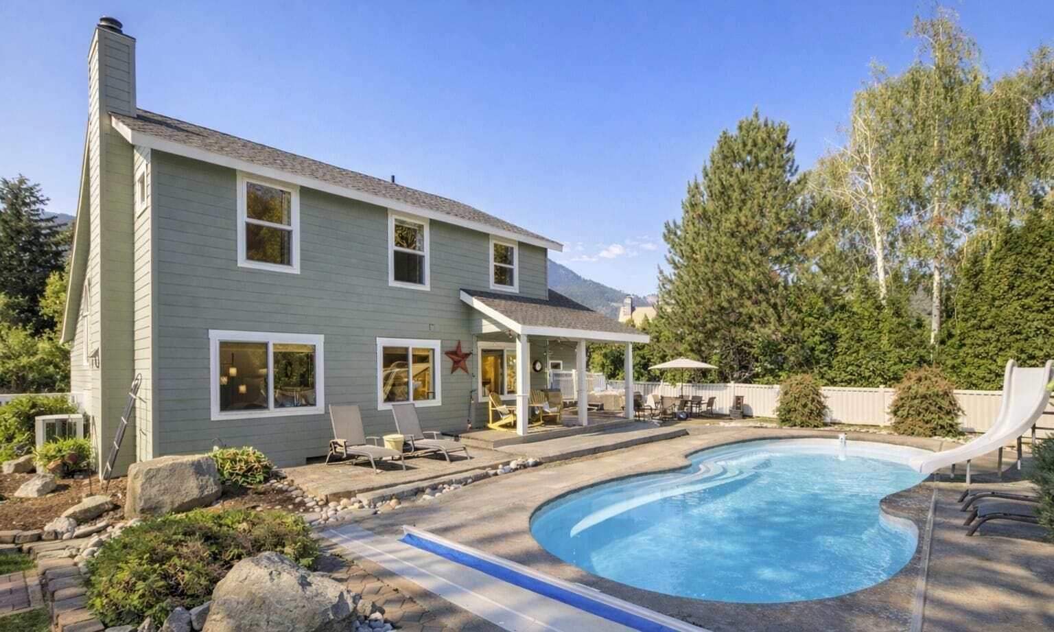 A two-story house with a swimming pool, outdoor seating, and a covered patio.