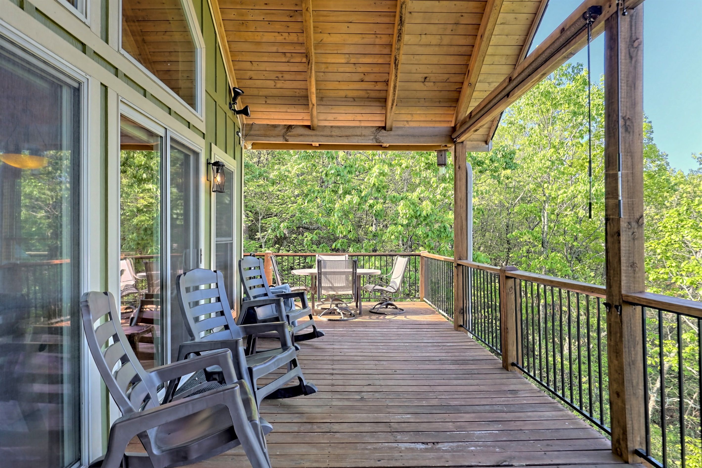 Une terrasse en bois avec des sièges extérieurs et une vue sur une forêt.