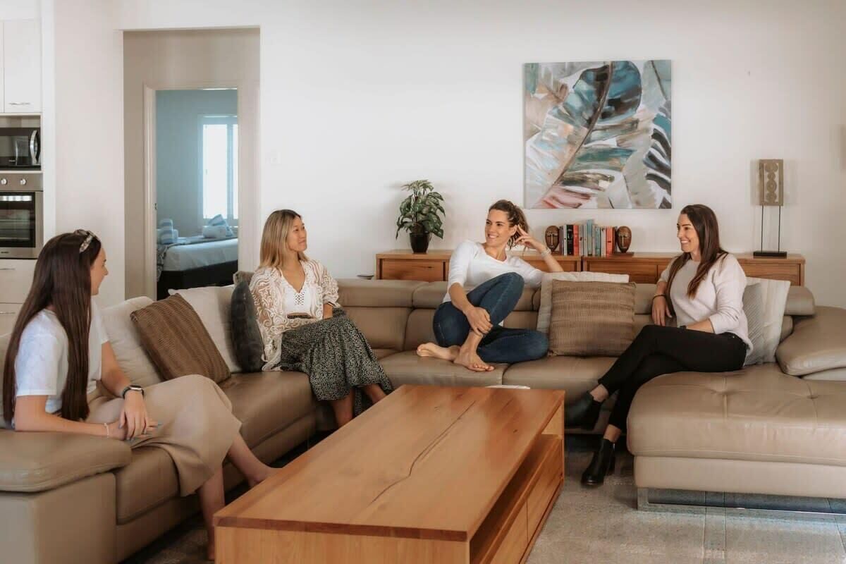 Uma sala de estar com um sofá, uma mesa de centro, uma estante de livros e um quadro na parede.