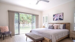 A bedroom with a large bed, a bench, a chair, a ceiling fan, and a view of the outdoors. - Golden Beach Family Home with Pool (Golden Beach)