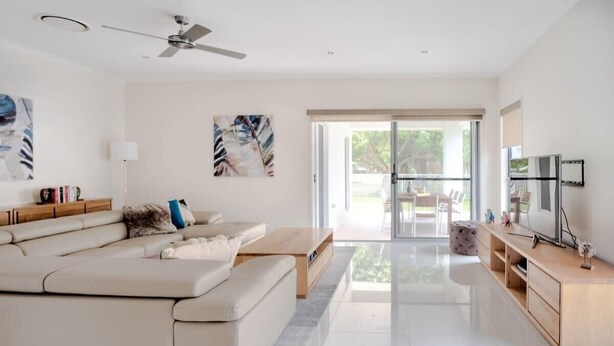 A modern living room with a sofa, coffee table, and TV stand. - Golden Beach Family Home with Pool (Golden Beach)