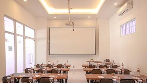 A conference room with tables set for a meeting, equipped with water bottles and glasses, a projector, and a large screen. - Dafam Express Jaksa Jakarta (Jakarta)
