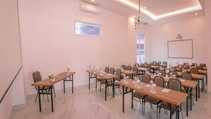 A conference room with multiple tables and chairs, air conditioning units, and a projector screen on the wall. - Dafam Express Jaksa Jakarta (Jakarta)