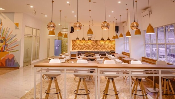 A modern dining area with a central island, multiple bar stools, hanging pendant lights, and a patterned backsplash. - Dafam Express Jaksa Jakarta (Jakarta)
