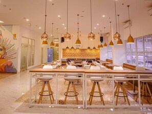 Un'elegante zona pranzo moderna con isola centrale, diversi sgabelli da bar, luci a sospensione e una parete di fondo decorata.