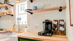 Una cocina con cafetera, estantes con vajilla y un ventanal con vistas.