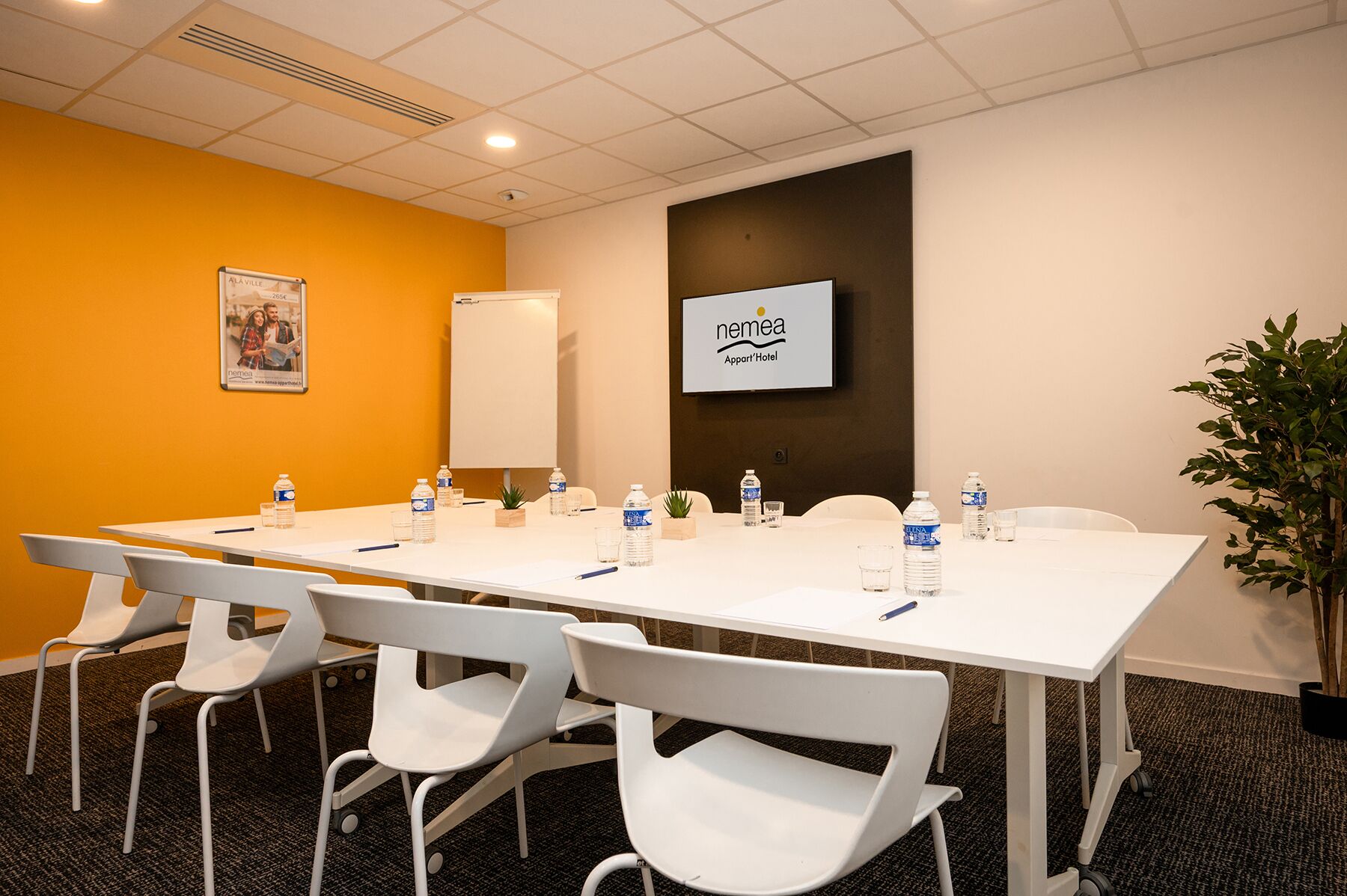 A conference room with a long table, white chairs, water bottles, and a whiteboard.