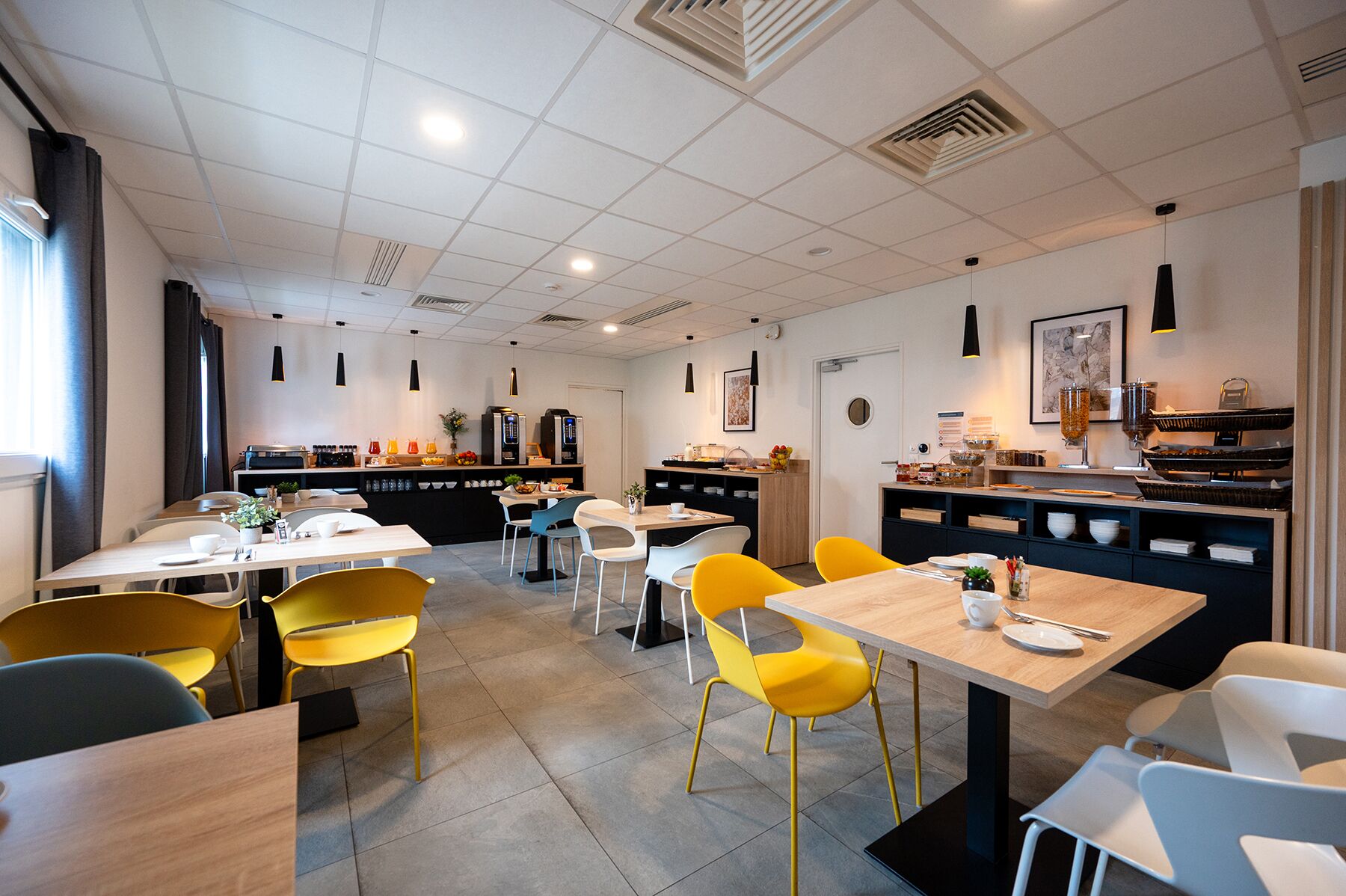 Una cafeteria moderna amb diverses zones d'ambientació, incloent taules i cadires, i una barra amb propostes de menjar i beguda.