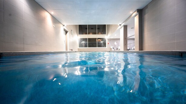 An indoor swimming pool with clear water, tiled walls, and a ceiling with recessed lighting. -  Nemea Appart Hotel Europe Velizy Villacoublay (Velizy-Villacoublay)