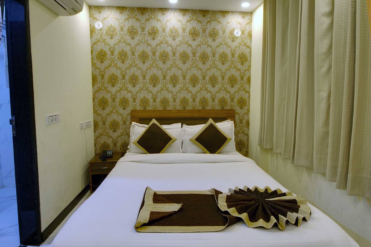 Uma cama bem arrumada com manta marrom e branca, um travesseiro decorativo e cabeceira de madeira.