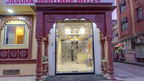 The entrance of Jasoda Heritage Hotel with ornate pillars and a glass door. - Jasoda Heritage Hotel Near Hawa Mahal (Jaipur)