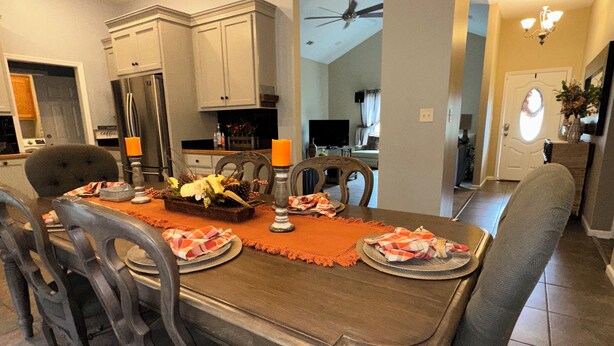 Un comedor con una mesa de madera dispuesta para cuatro personas, rodeada de sillas oscuras.