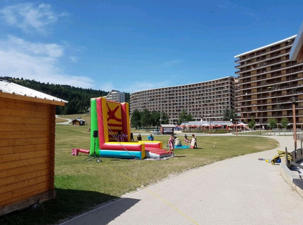 Un hotel con un edificio grande de varios pisos, un área verde con una estructura inflable colorida y un sendero pavimentado.