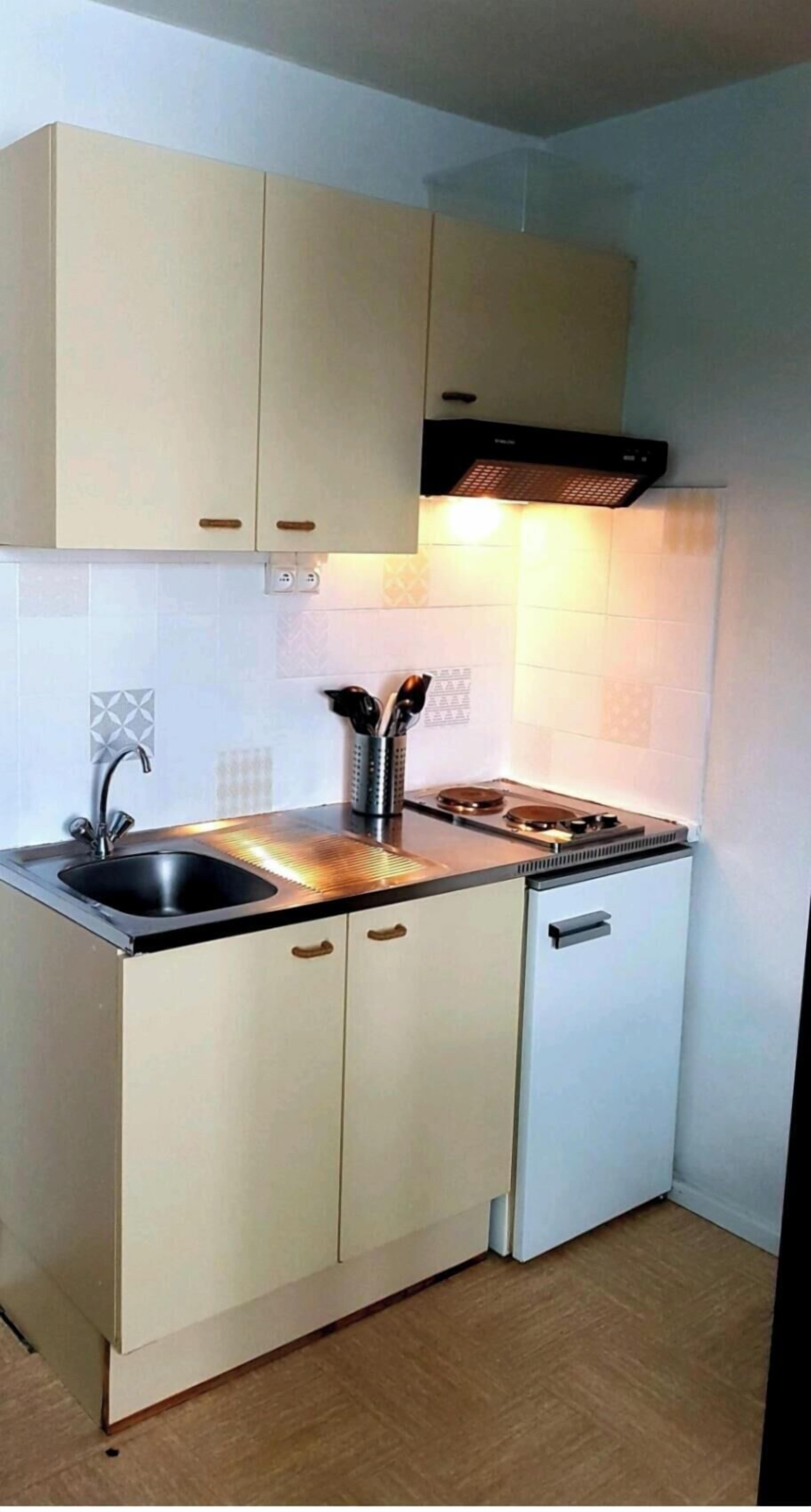 A compact kitchen with a sink, stove, and cabinets.