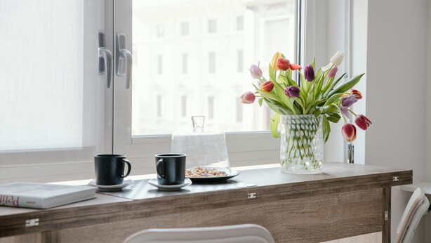 A wooden desk with a vase of tulips, a coffee cup, and a book. - MARK'S GALLERY - By MyHomeInComo (Como)