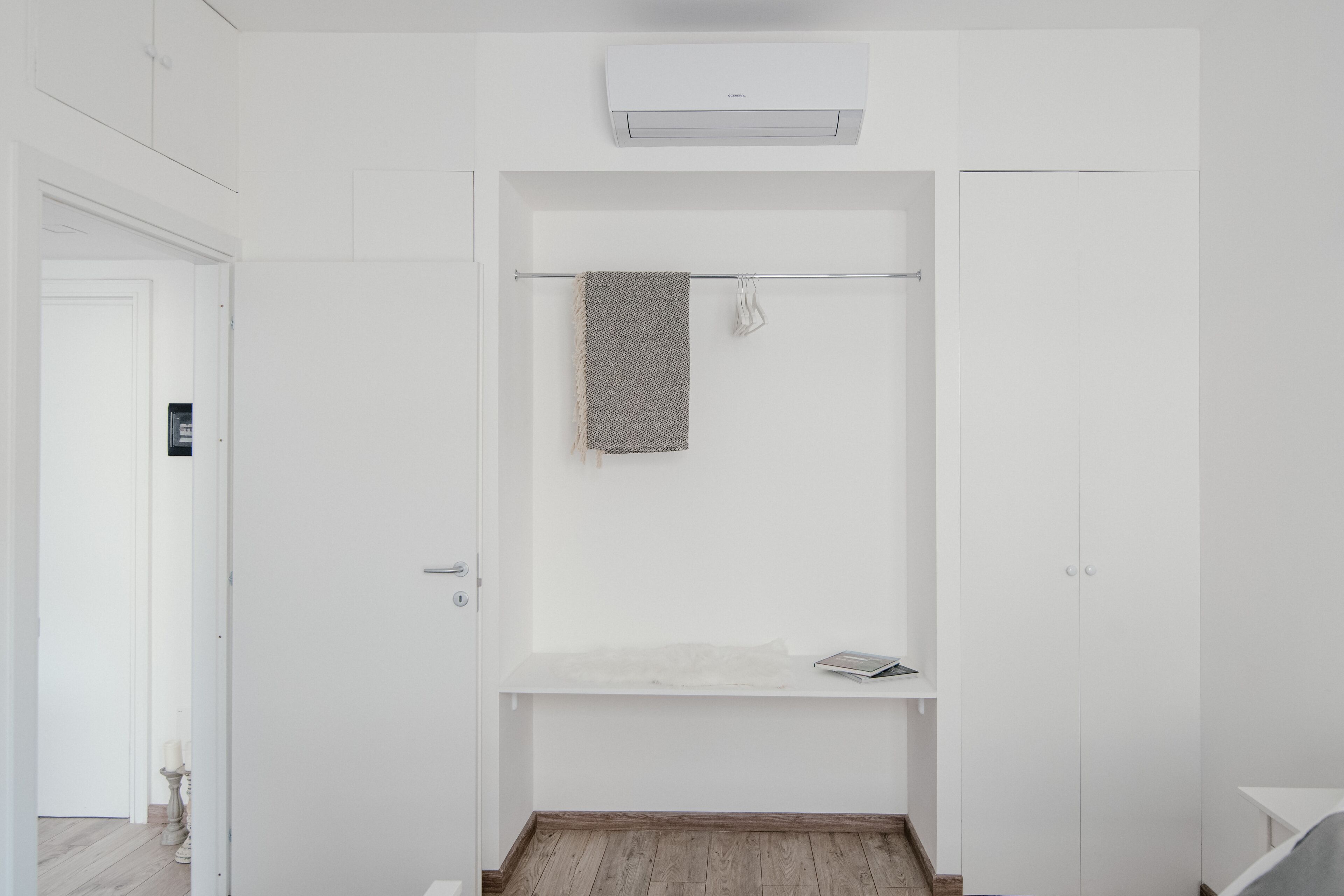 Une salle de bain minimaliste avec un porte-serviettes, une étagère et une armoire blanche.