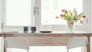 A wooden desk with a vase of tulips, a coffee cup, and a plate of food near a window. - MARK'S GALLERY - By MyHomeInComo (Como)