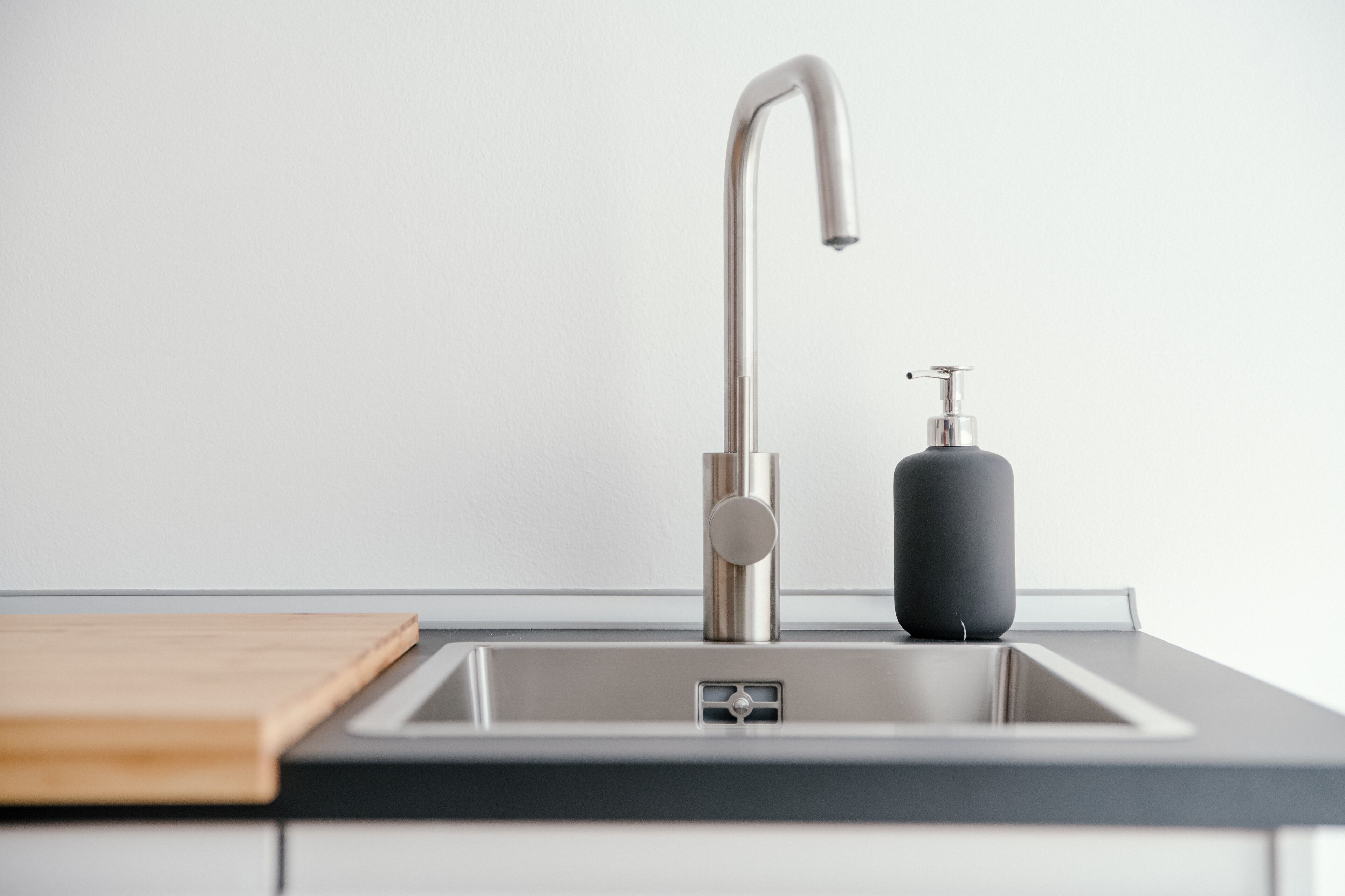 A modern kitchen sink with a stainless steel faucet and a soap dispenser.