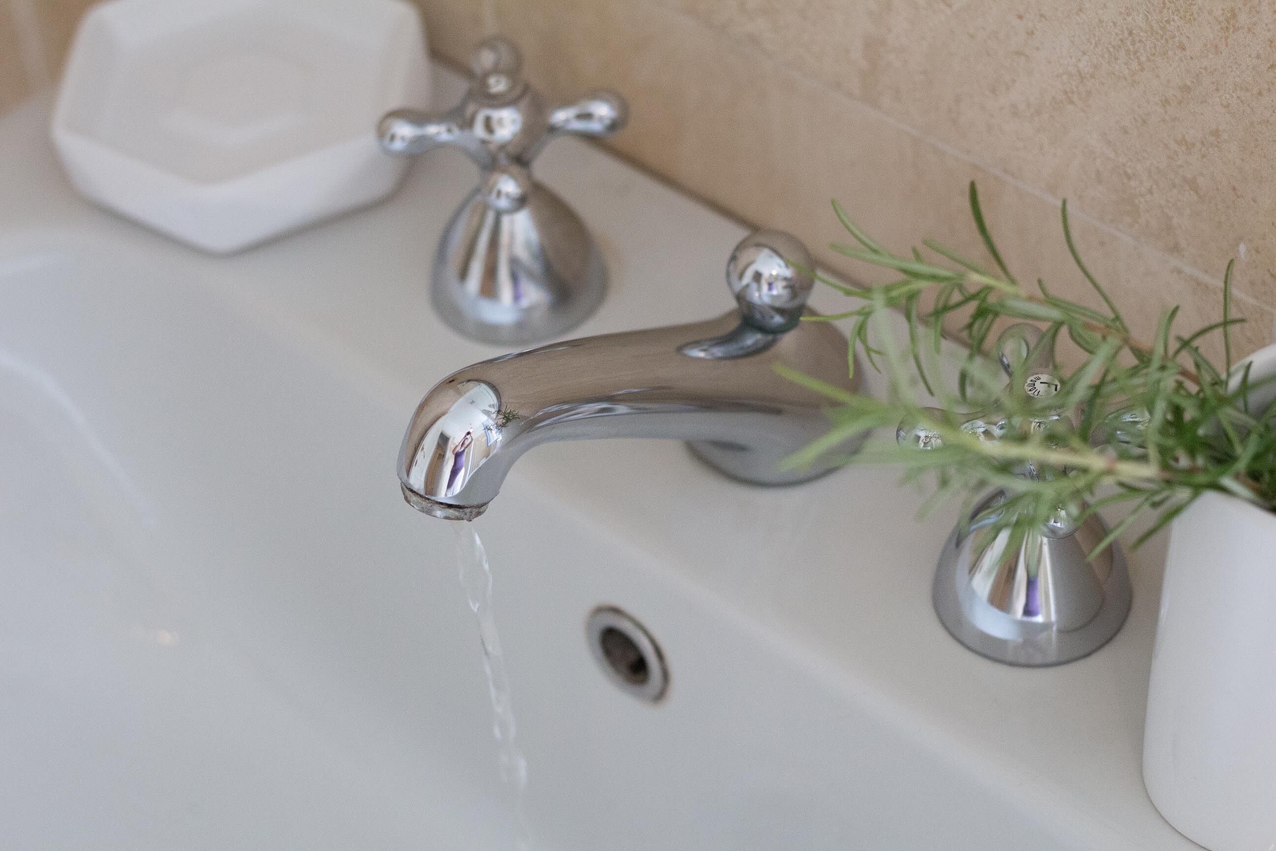 A bathroom sink with a chrome faucet and a small white soap dish.