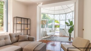 A modern living room with a sectional sofa, a small round table, and a glass partition leading to an outdoor area. - Como Lake Vista by My Home in Como (Blevio)