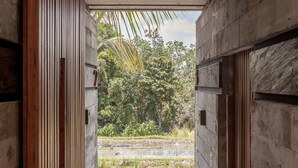 A corridor with wooden slats and a concrete ceiling leading to an outdoor area with greenery. - Batukaru Private Pool Suite 3 (Canggu)
