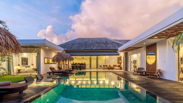 A modern pool area with lounge chairs and a dining area.